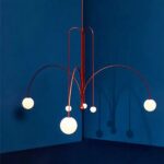 Terracotta curved branch chandelier with white glass globes against a blue wall