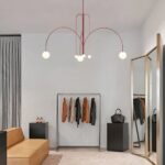 Red curved-arm chandelier with five white glass globes above a clothing rack