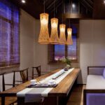 Four woven bamboo cone pendant lights above a long wooden dining table
