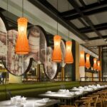 Row of woven bamboo cone pendant lights glowing above a green banquette