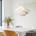 White layered petal shaped pendant lamp above a dining table