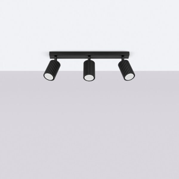 Black ceiling bar fitted with three fluted cylindrical spotlights