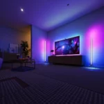Pair of tall LED corner floor lamps glowing in shifting colours beside a TV