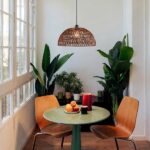 Dark woven rope dome pendant hanging above a café table between plants